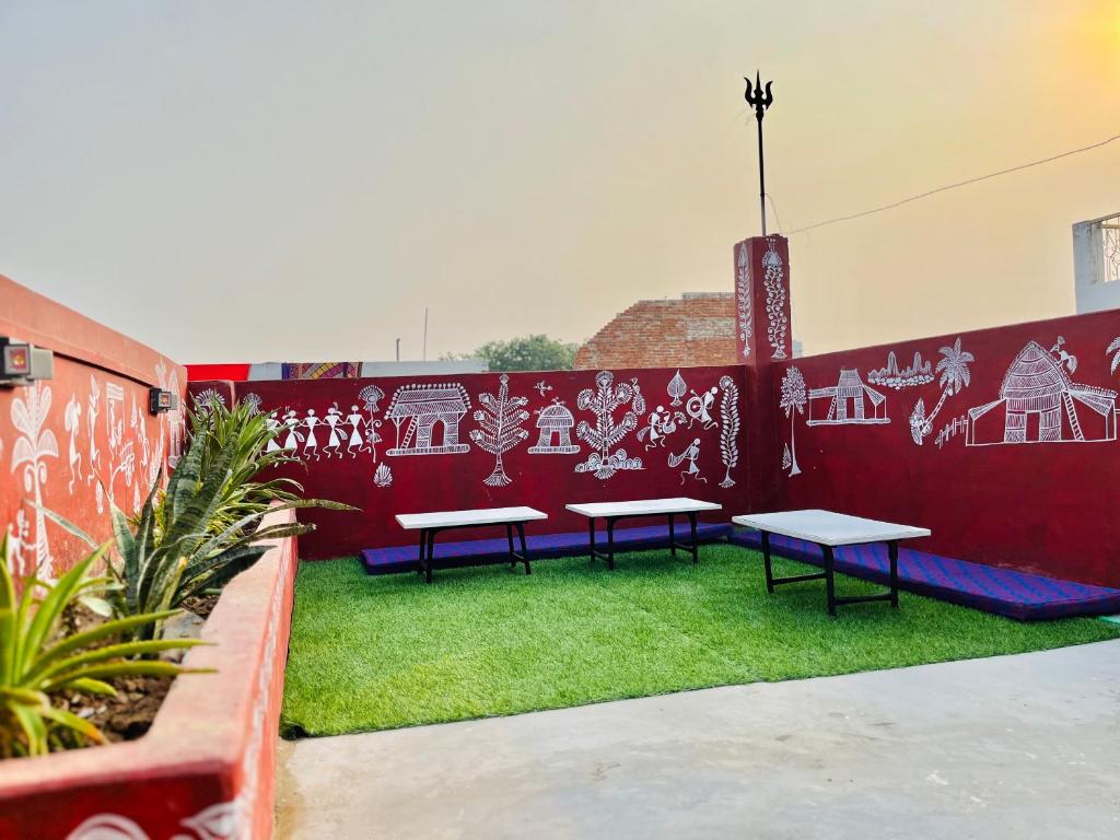 two benches sitting on grass next to a red wall at Holy River Stays in Varanasi