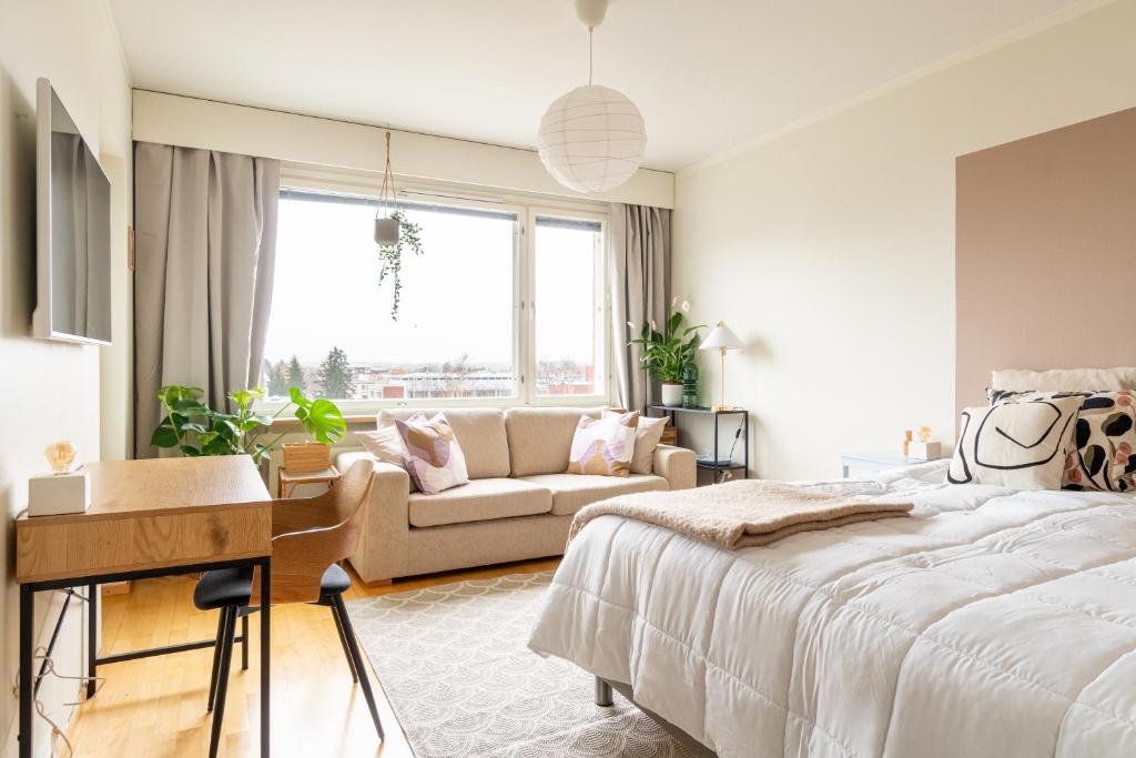 een witte slaapkamer met een bed en een bank bij Kodikas asunto Tikkurilassa in Vantaa
