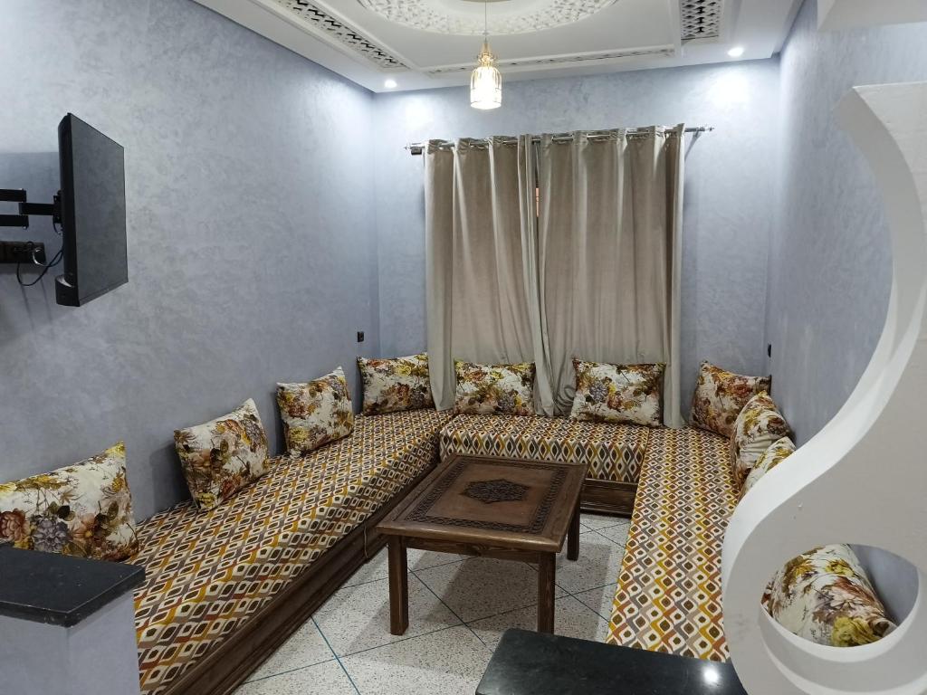 Habitación con sofá con almohadas y mesa. en Residence Adnan luxury Appartments en Ouarzazate