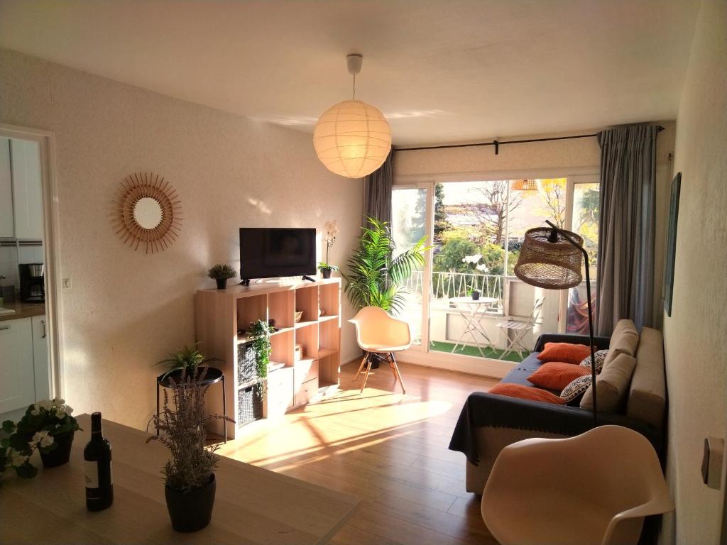 ein Wohnzimmer mit einem Sofa und einem TV in der Unterkunft Résidence du Parc fleuri de Lyon Cœur Lyon8 PKG free 95m2 in Lyon
