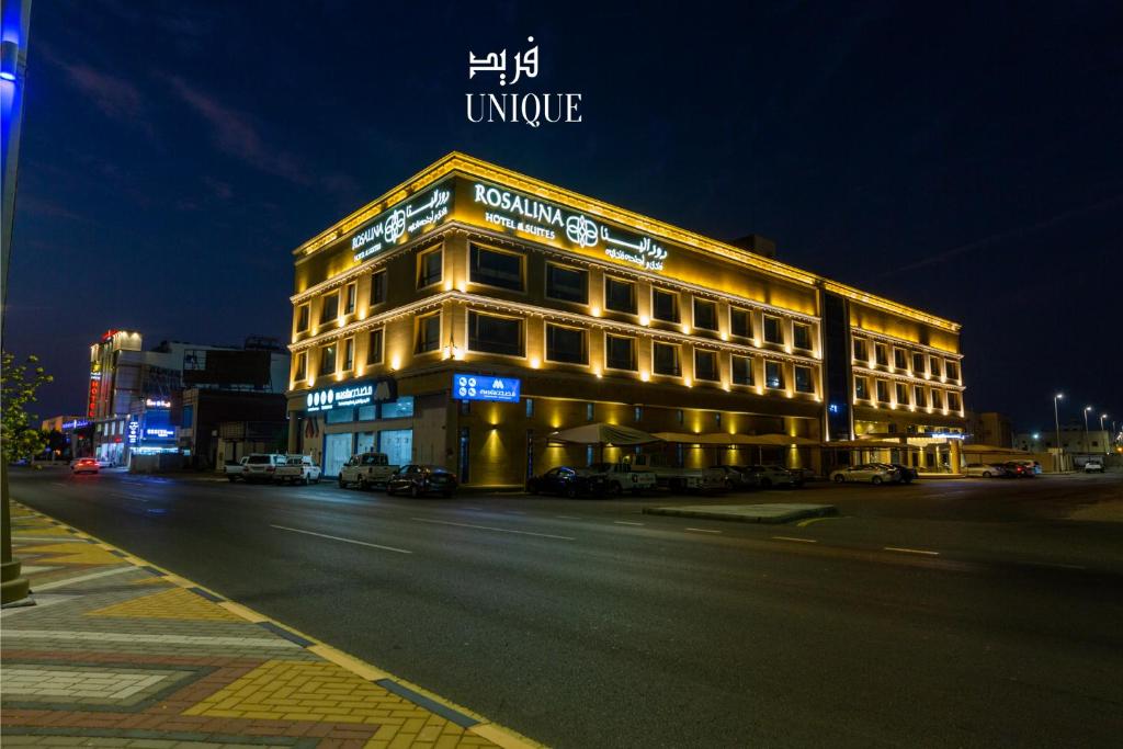 un bâtiment situé dans une rue de la ville la nuit dans l'établissement فندق روزالينا, à Yanbu