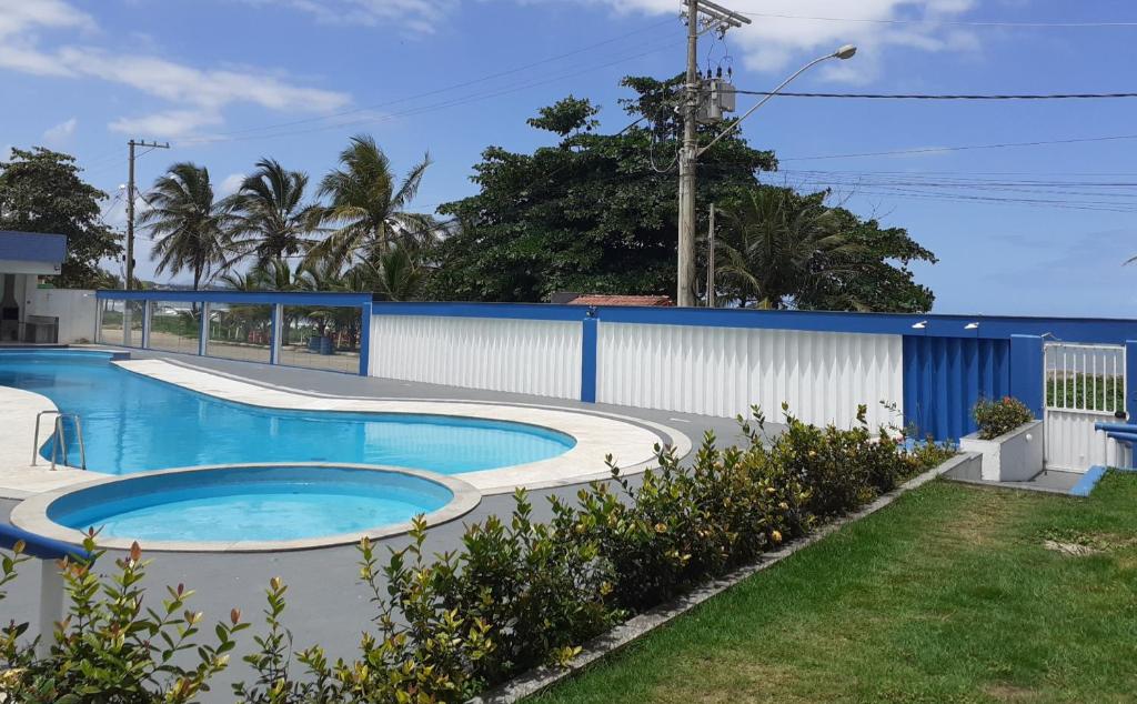 a swimming pool in front of a blue building at COBERTURA Duplex com Visao do Mar, Village das ondas in Piúma