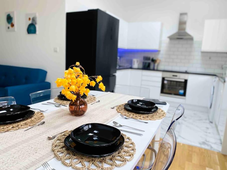 a table with black plates and yellow flowers on it at Modern and Comfy 1-Bedroom Flat in Wembley in London