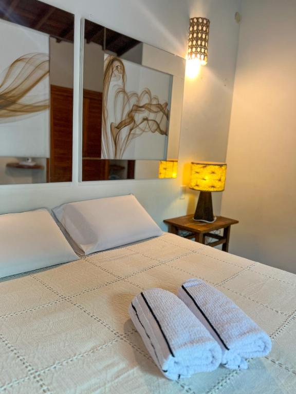 uma cama branca com duas toalhas em cima em Pousada Casa Mucugê em Porto Seguro