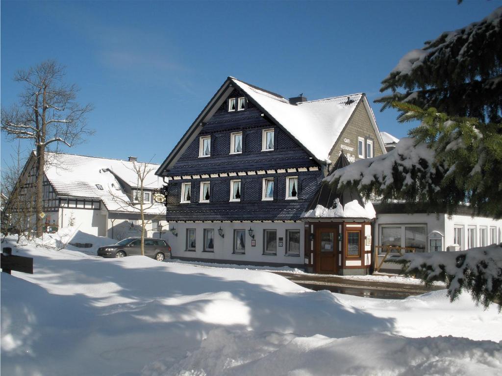 Une grande maison noire et blanche dans la neige dans l'établissement Landhotel Gasthof zur Post, à Winterberg