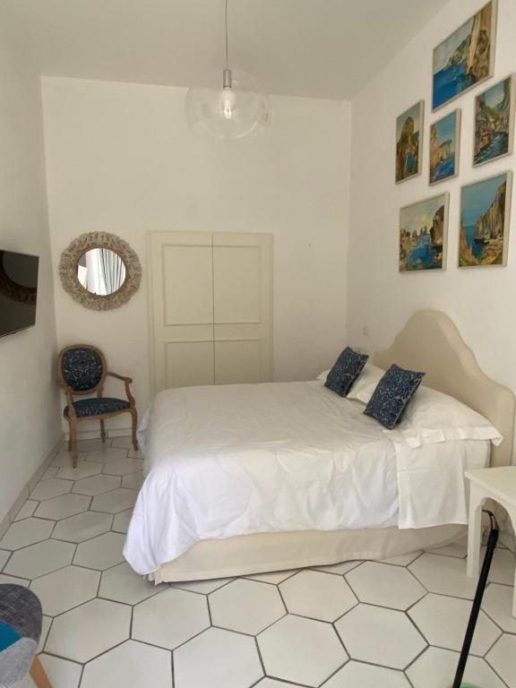 una camera bianca con un letto e una sedia di ELISA ROOMS a Capri
