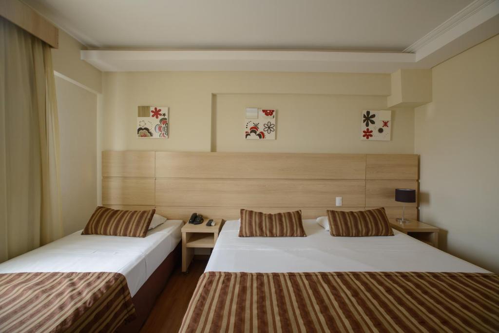 a hotel room with two beds and a desk at Faro Hotel Atibaia in Atibaia