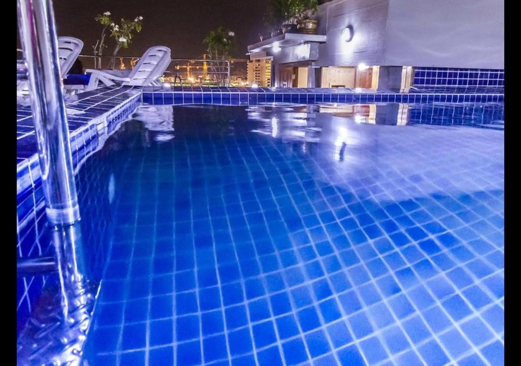 a large blue swimming pool with white chairs in it at Patong Dynasty Royal Hotel in Patong Beach