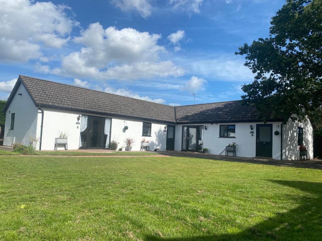 a white house with a large grass yard at Lytton Tree Lodge Reydon in Reydon