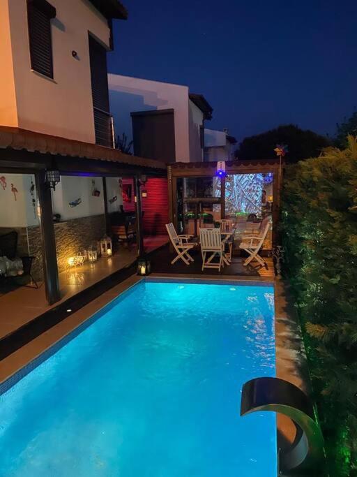 ein Schwimmbad vor einem Haus in der Nacht in der Unterkunft Denizin dibinde özel havuzlu in Seferihisar