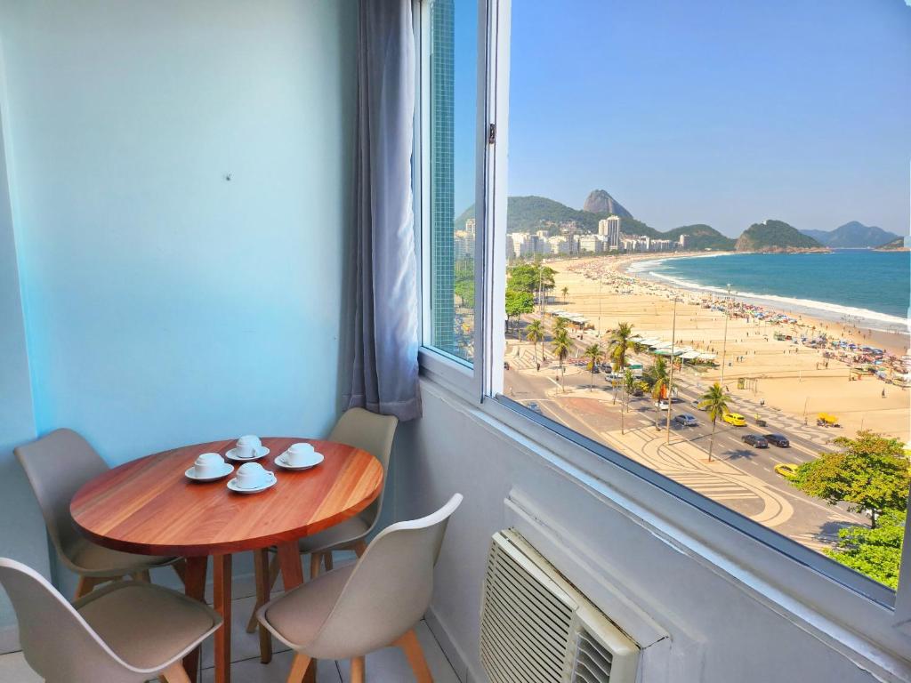 a table and chairs in a room with a view of the beach at Beira-mar com vista da Praia TC902 in Rio de Janeiro