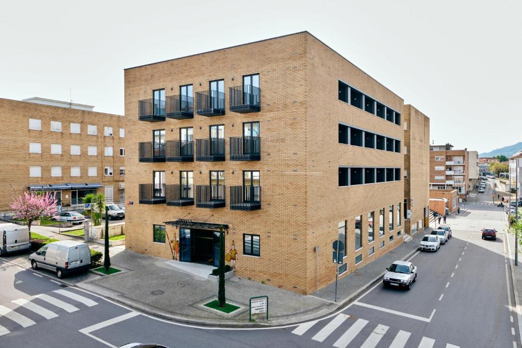 een groot bakstenen gebouw met auto's geparkeerd op een straat bij Hotel O Guerreiro in Ponte da Barca