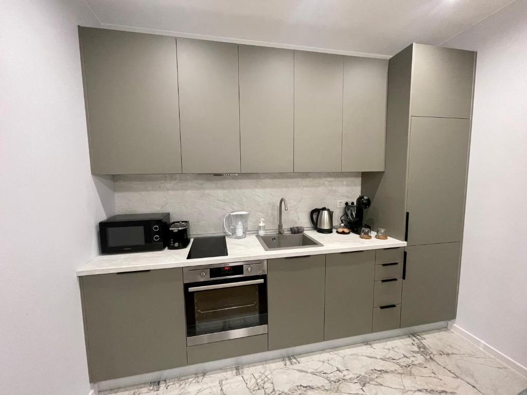 a kitchen with white cabinets and a sink at Vanquish Central Apartment in Varna City