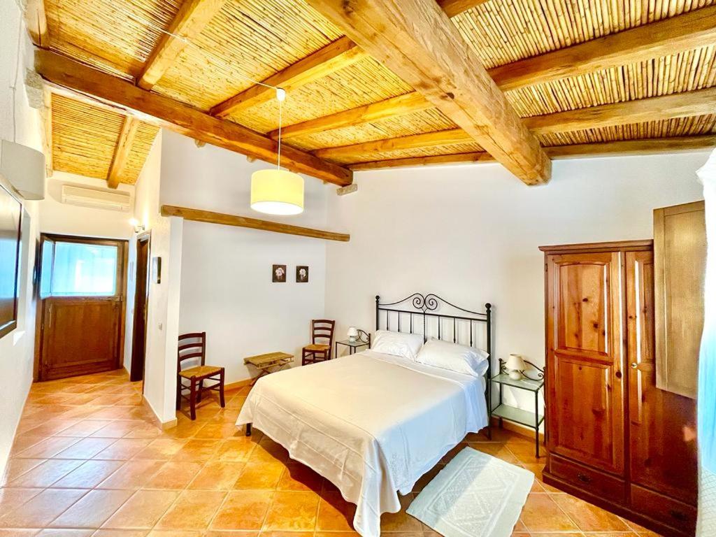 een slaapkamer met een bed en een houten plafond bij Agriturismo Li Scopi in San Teodoro