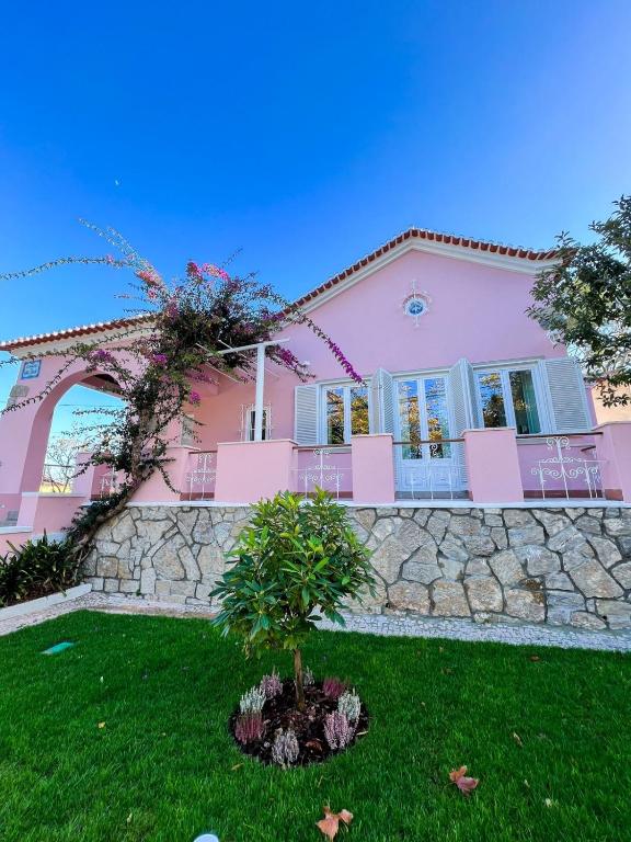 a pink house with a tree in the front yard at Chalet do Eléctrico 92' in Sintra