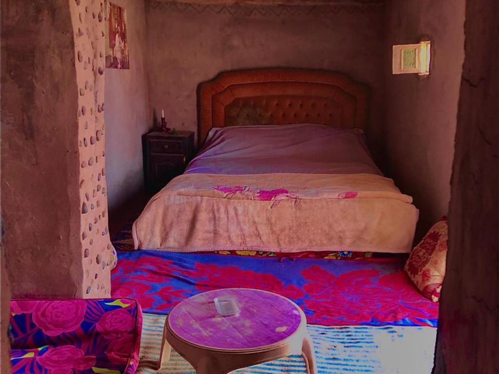 a small bedroom with a bed and a table at Bivouac Liguera chez Ahmed in Mhamid