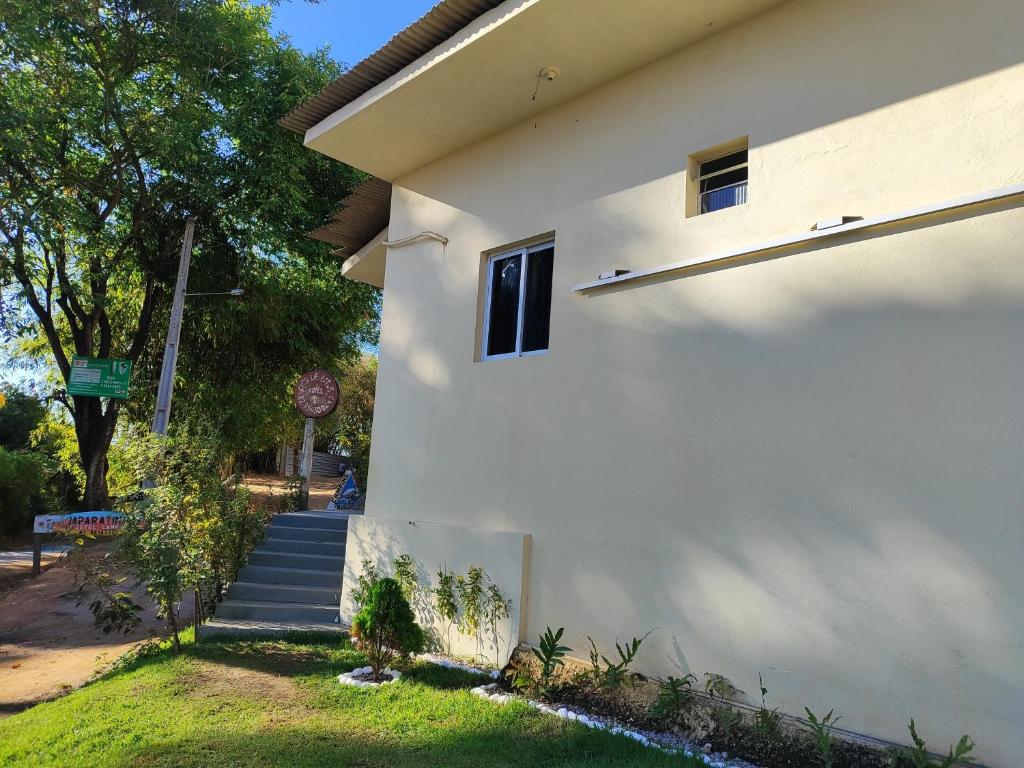 a white house with a staircase next to it at Apartamento Inteligente in Japaratinga