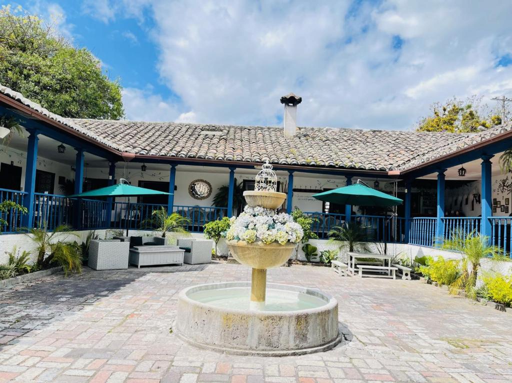 una fontana con fiori di fronte a un edificio di Hacienda Hosteria Chorlavi a Ibarra