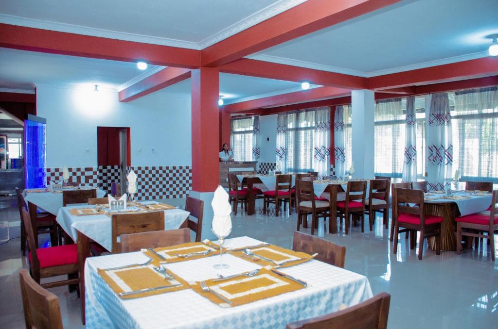 - une salle à manger avec des tables, des chaises et des fenêtres dans l'établissement Kinindo Light Hotel, à Bujumbura