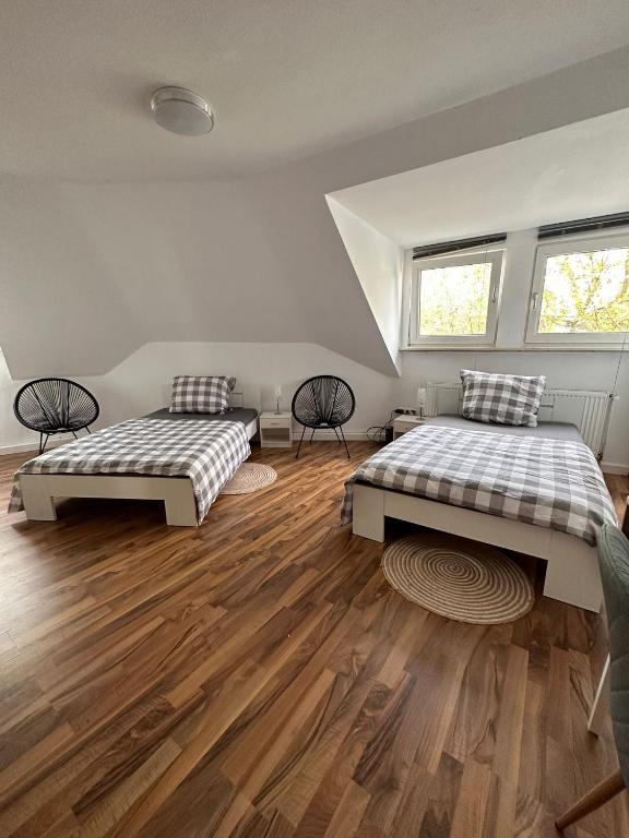 2 łóżka w pokoju z drewnianymi podłogami i oknami w obiekcie Zimmer im Zentrum - in der Nähe zum Hauptbahnhof w mieście Paderborn