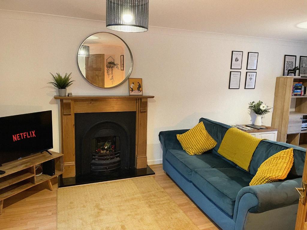 a living room with a blue couch and a fireplace at 3 bed home in Cheltenham Town Centre with FREE PARKING for 1 car in Cheltenham