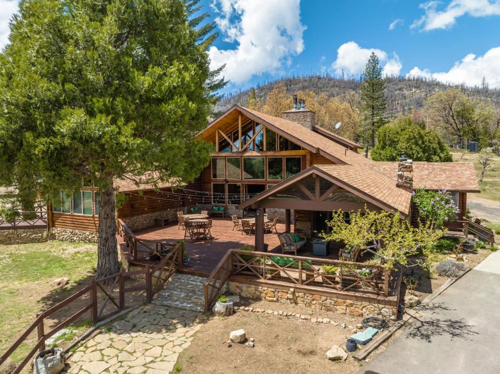 an exterior view of a log home with a tree at Gorgeous North Fork Cabin Near Bass Lake! in North Fork