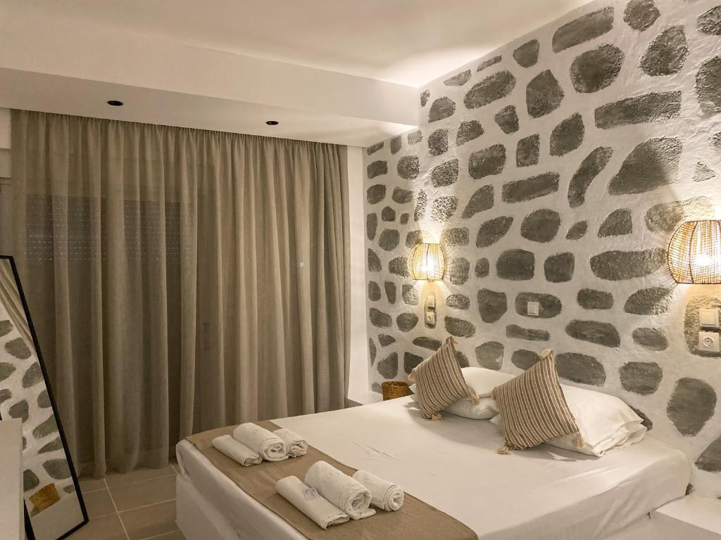 1 dormitorio con cama y pared de piedra en Ladiko Inn Hotel Faliraki -Anthony Quinn Bay en Faliraki
