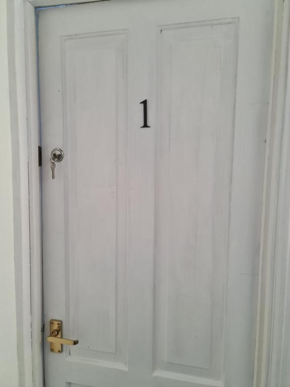 une porte blanche avec le numéro un sur elle dans l'établissement Guest house room 1, à Haverfordwest