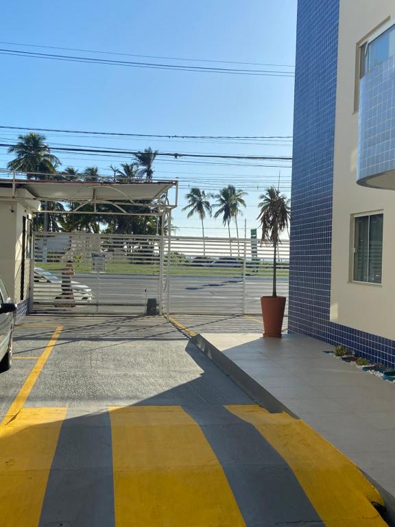 a parking lot with a building and palm trees at Apart - em frente á praia dos milionários- Ilhéus in Ilhéus