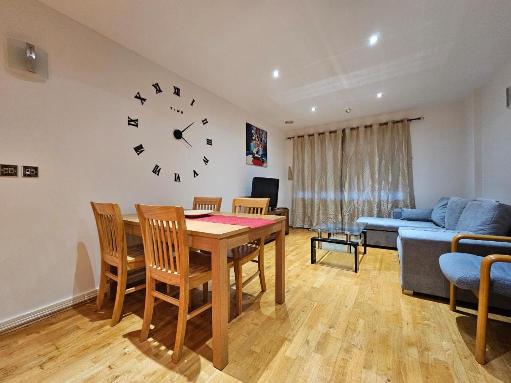 uma sala de estar com uma mesa e um relógio na parede em Cozy Flat close to central London em Londres