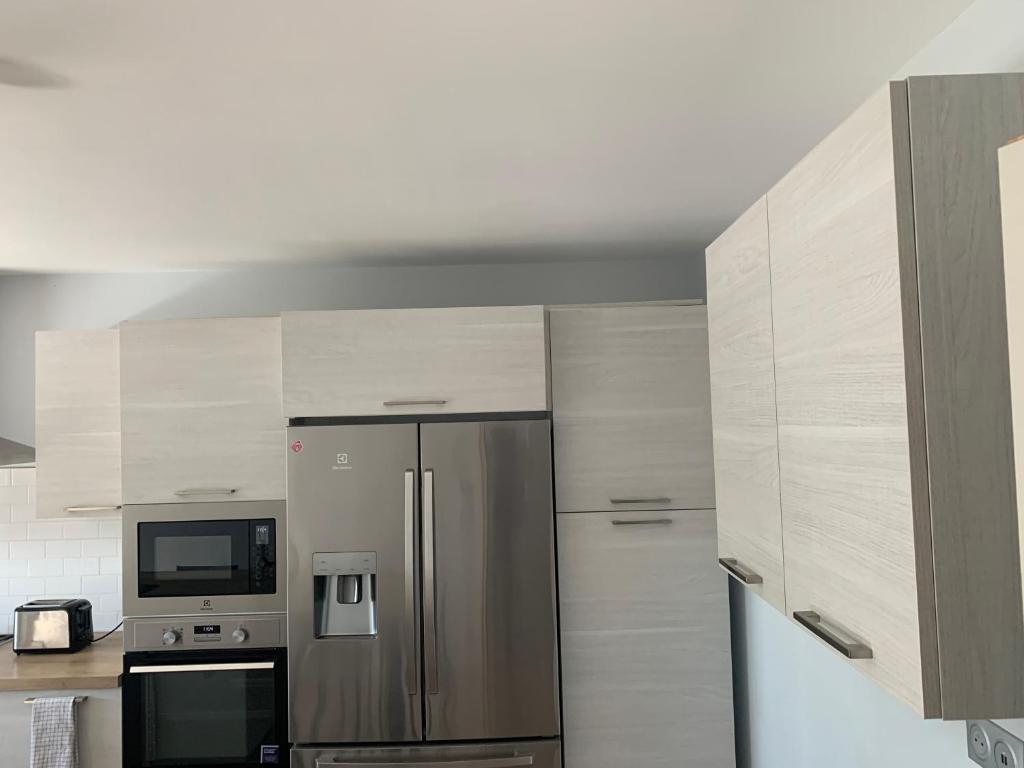 a kitchen with a stainless steel refrigerator and a microwave at Maison calme&#47;Chambre privée&#47;Clim+TV&#47;Pétit dejeuner inclu&#47;tout confort in Nevers