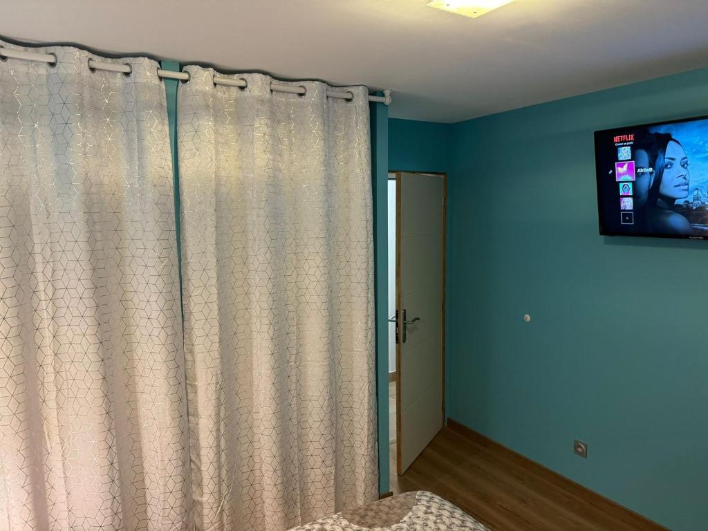 a bedroom with a curtain and a tv on the wall at Maison calme&#47;Chambre privée&#47;Clim+TV&#47;Pétit dejeuner inclu&#47;tout confort in Nevers