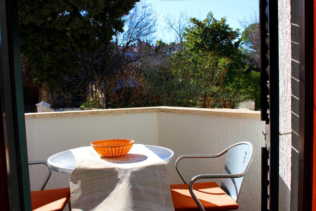a table and chairs on a balcony with a bowl on it at Alison Apartments in Premantura