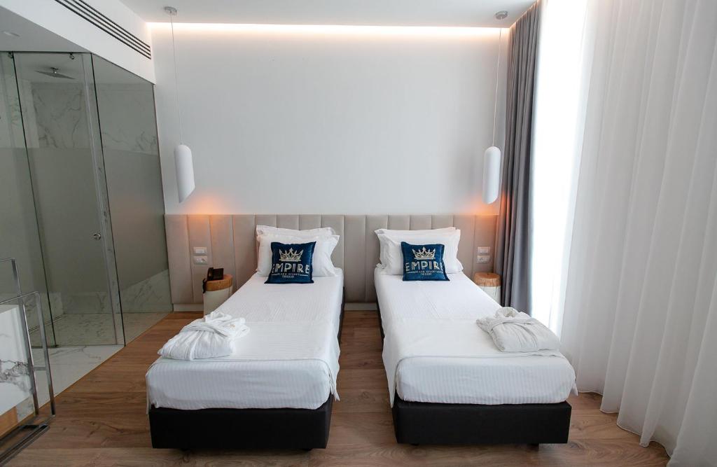 two twin beds in a room with a mirror at Empire Beach Resort ADULTS ONLY in Dhërmi
