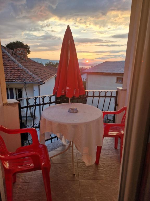 a table with a red umbrella on a balcony at Apartments Picioski in Peštani