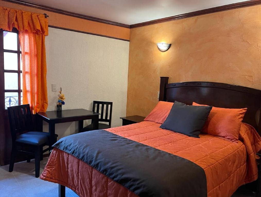 1 dormitorio con cama, mesa y escritorio en Hotel Paraiso Real Plus, en Mineral del Monte