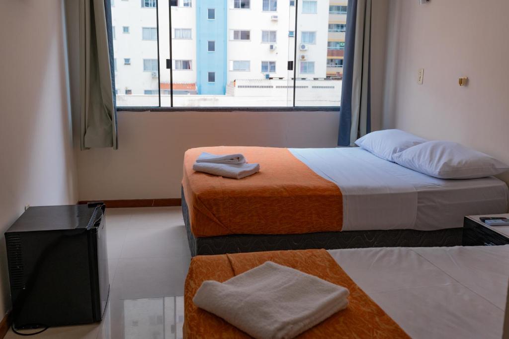 a hotel room with two beds and a window at HANNA Balneário Hotel in Balneário Camboriú
