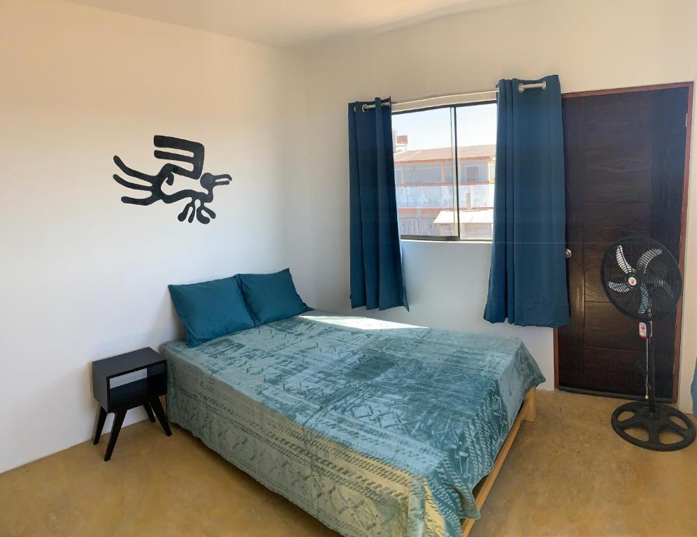a bedroom with a bed and a window with a fan at Tayta Surf House in Lobitos