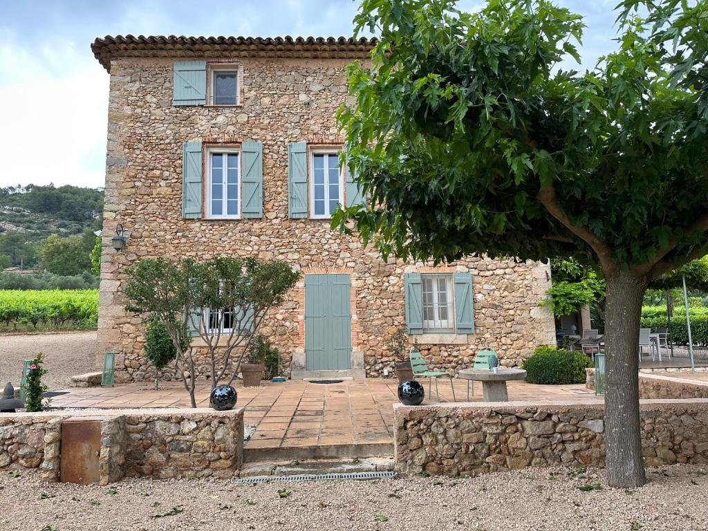 una casa de piedra con un árbol delante en Le verger, en Le Val
