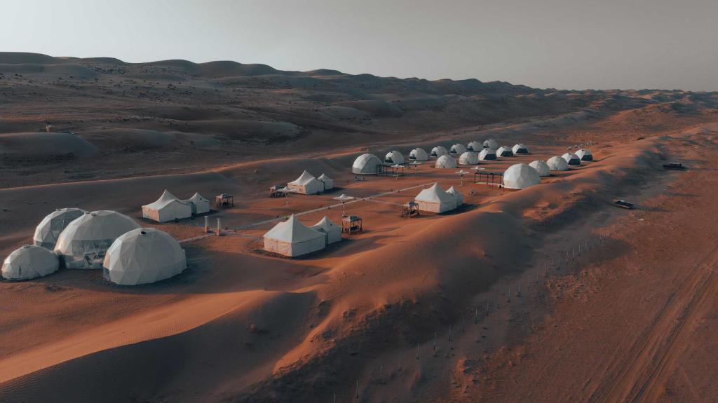 um grupo de tendas num deserto com uma estrada de terra em Luxury Desert Camp em Al Wāşil