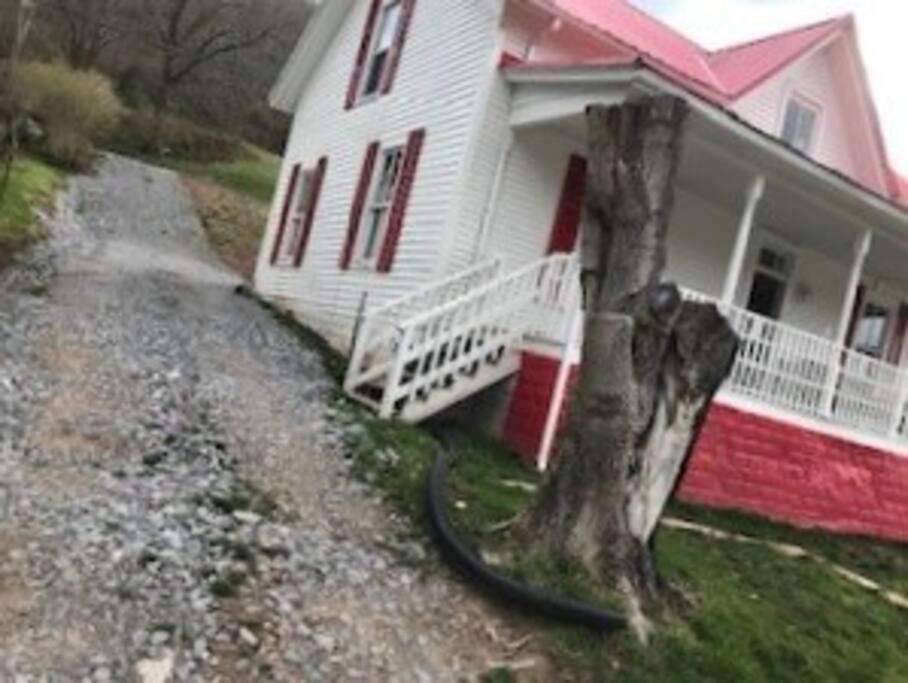 a house with a tire leaning against a tree at Red Roof Home Accommodates 10 people! in Tazewell