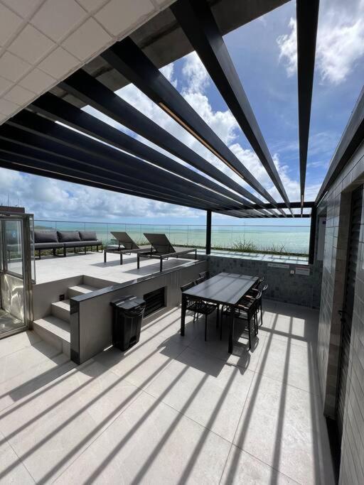 un patio con tavolo e panche sul balcone di Loft Luxo para 4 pessoas vista mar a Cabedelo