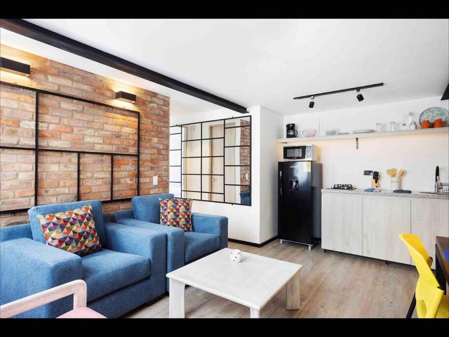 uma sala de estar com um sofá azul e uma cozinha em Stylish 2BR Chapinero Apt - Prime Location! em Bogotá