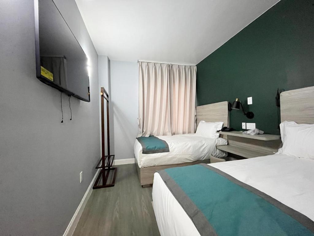 a hotel room with two beds and a television at Starlight Hotel Near LGA Airport in Queens