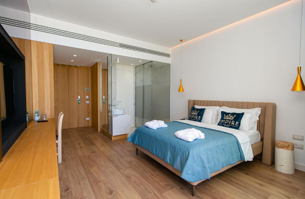 a bedroom with a large bed and a bathroom at Empire Beach Resort ADULTS ONLY in Dhërmi