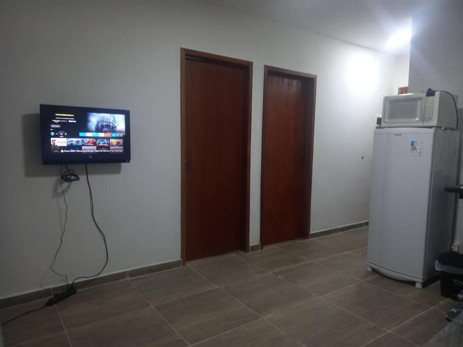 um quarto com uma televisão e um frigorífico em Casa em Unamar, Cabo Frio - com piscina privativa em Cabo Frio