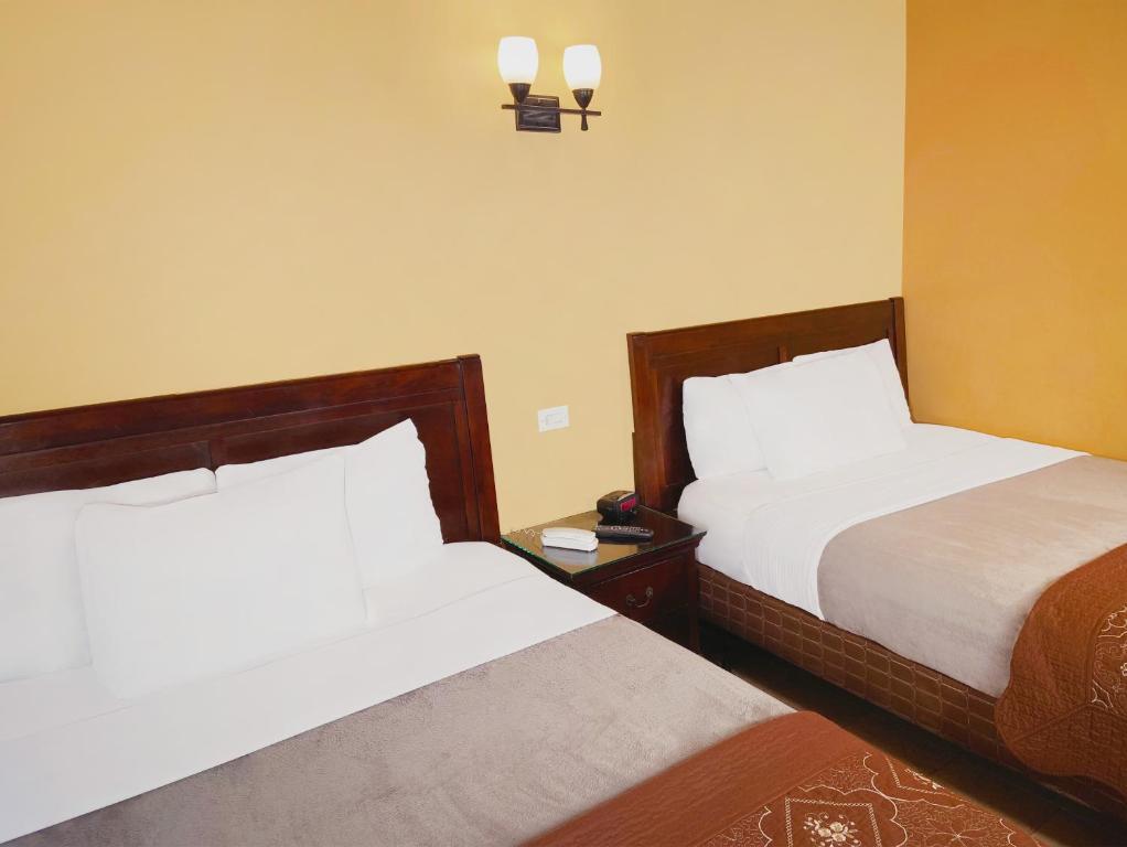 a hotel room with two beds and a clock on the wall at El Patio Inn - Near Universal Studios Hollywood in Los Angeles