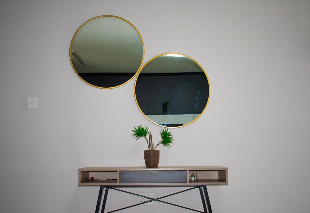un tavolo con due specchi e una pianta in vaso di Candymoore apartment a Sandton