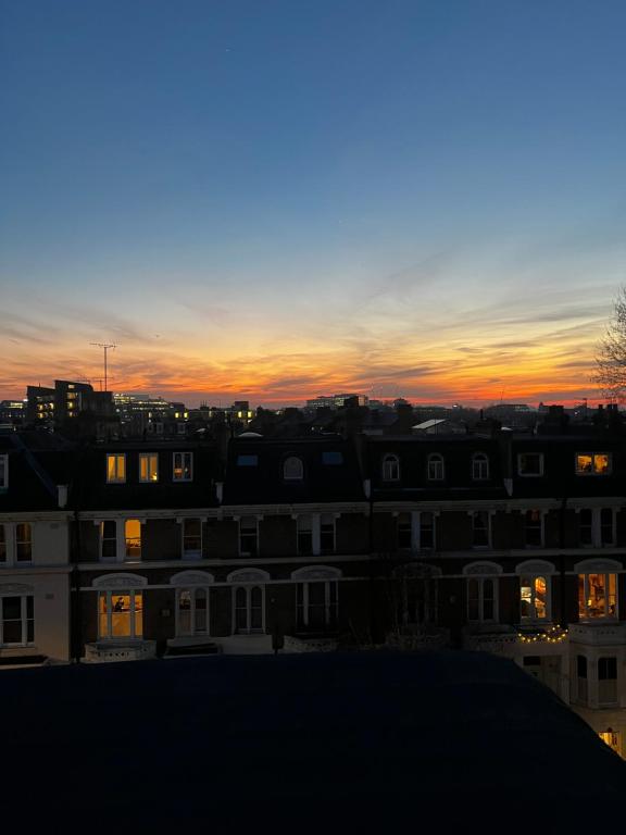 a sunset over a city with houses and buildings at Modern studio apartment in West Kensington in London