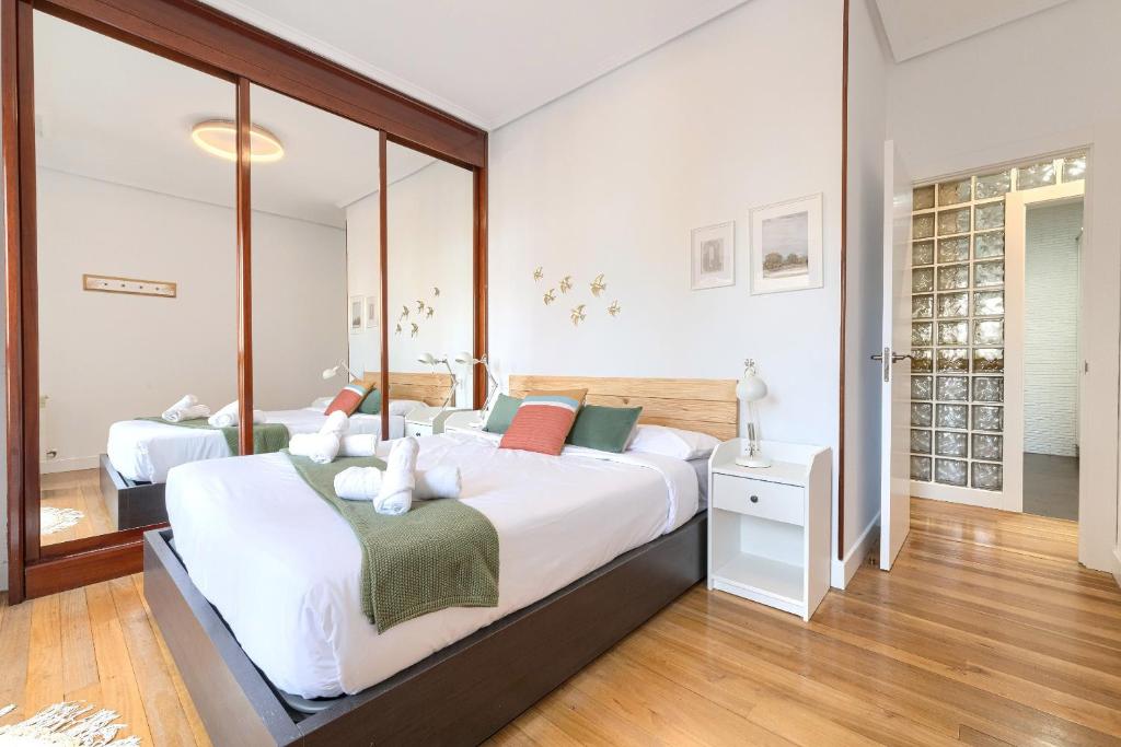 um quarto com uma cama grande e um espelho em Iturribide Hogar Moderno junto al Metro em Bilbau